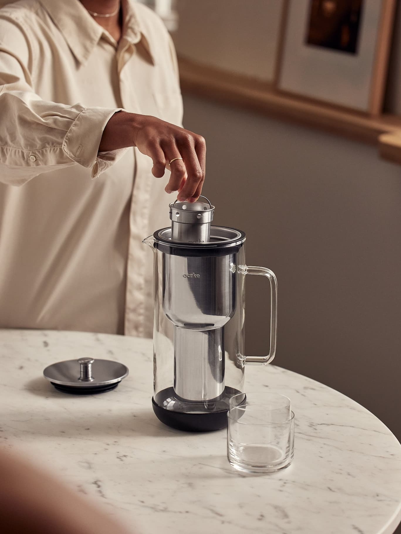 Inserting the stainless steel filter into the Aarke Purifier on a marble table.