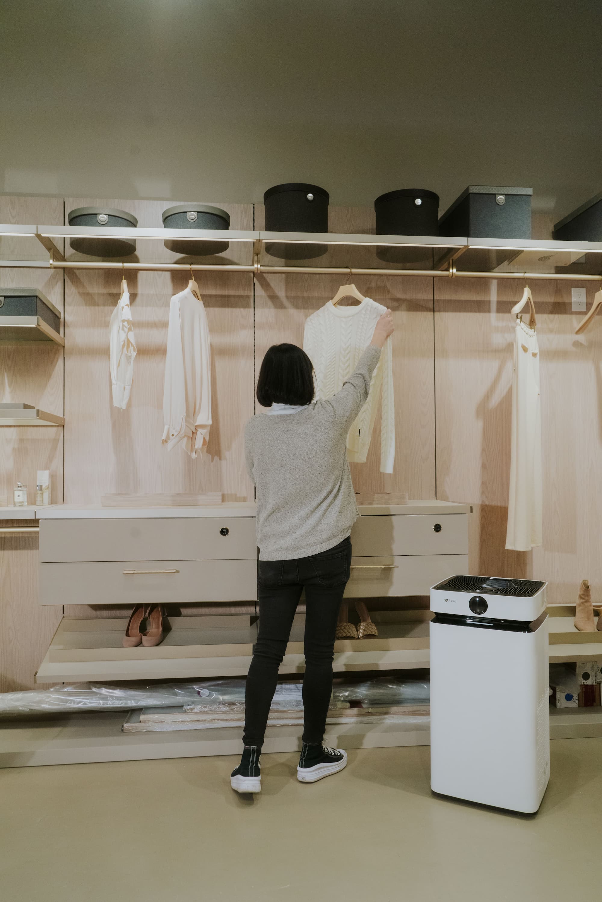 Person hanging clothes next to Airdog X8 Air Purifier