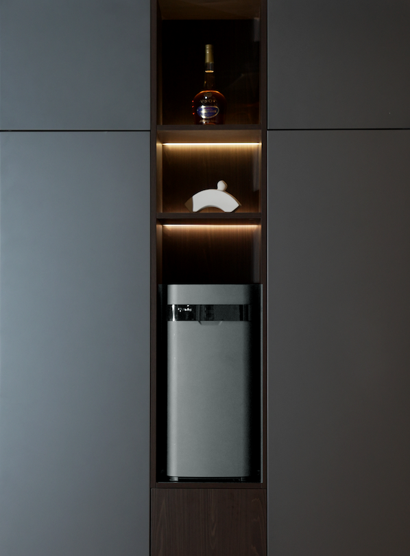 Airdog in a cabinet underneath a sculpture and a glass bottle