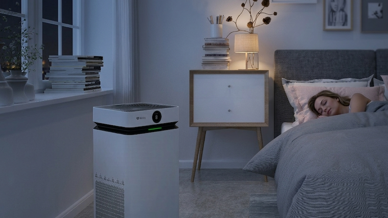 Person sleeping on bed with an air purifier