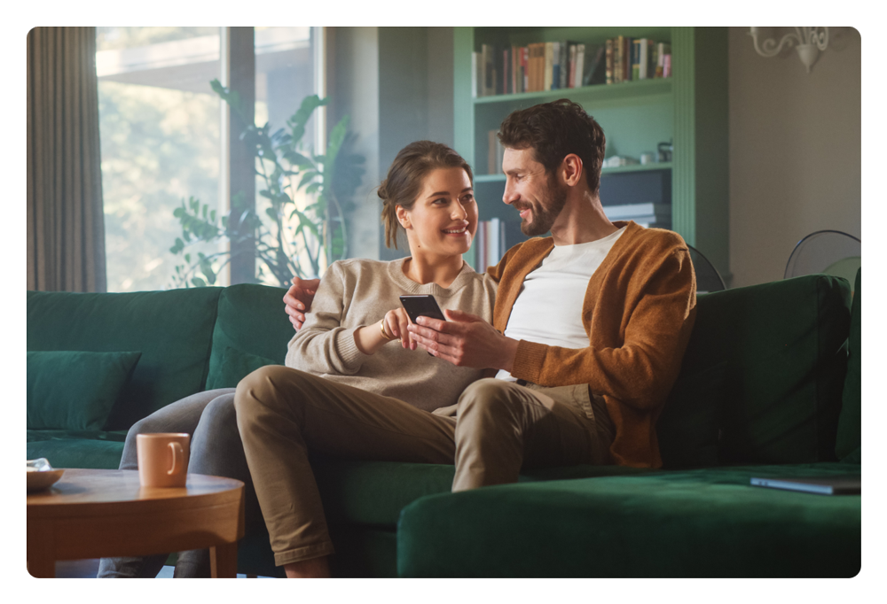 People looking at their phone while sitting on the couch.