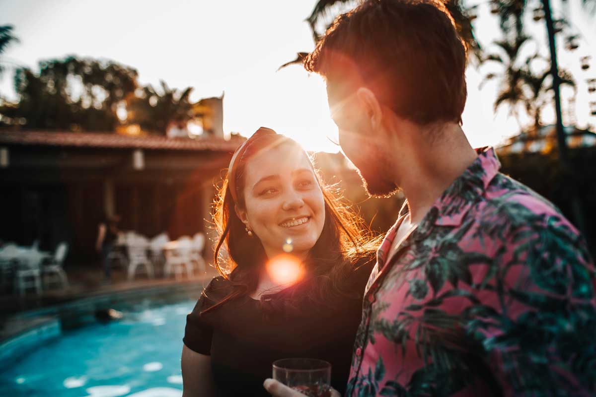 Couple by pool at sunset drinking Atla water.
