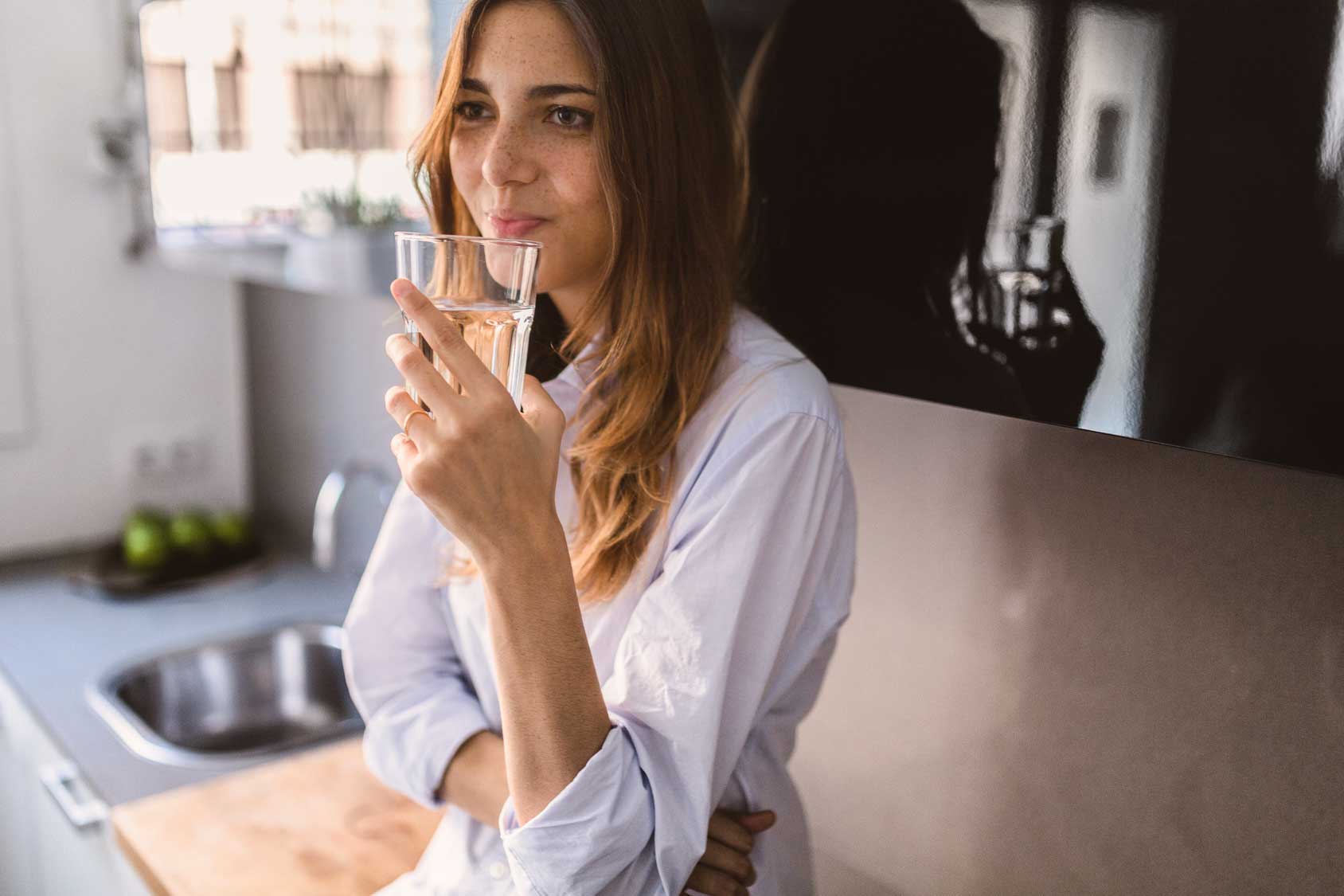 Woman holding a glass of Atla water.