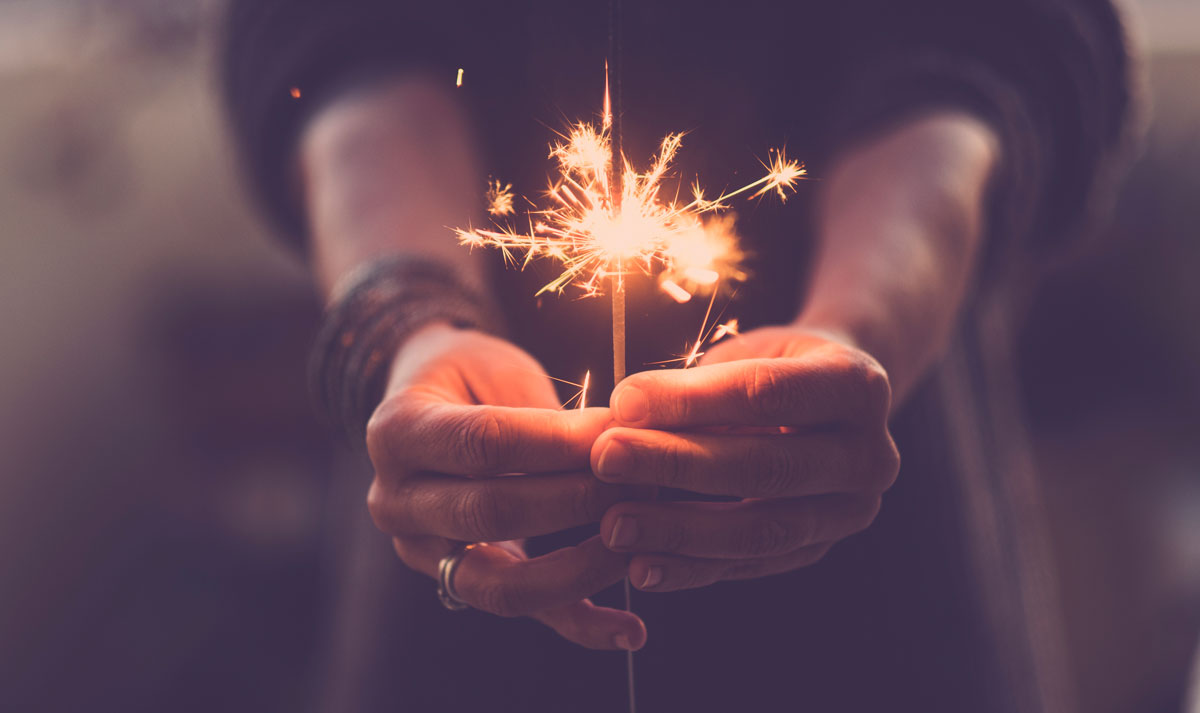 Woman holding sparkler in her hands.