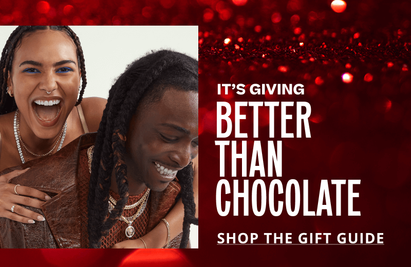 Female and male model smiling, wearing bold gold and diamond jewelry. Giving: Better than chocolate. Click here to shop the gift guide