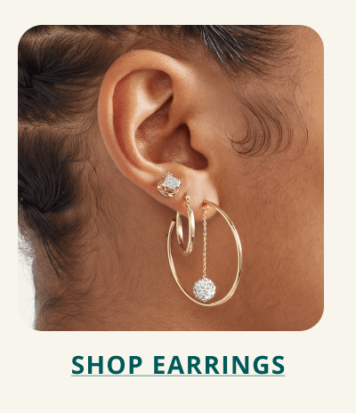 An ear stack with gold hoops, diamond studs and hanging drop earrings. Click here to shop earrings