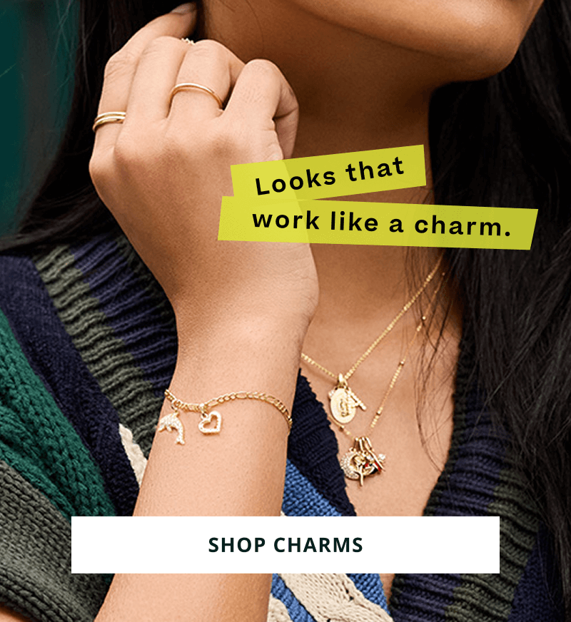Model wearing gold necklaces and bracelets, with unique and personalized gold charms. Looks that work like a charm. Click here to shop charms