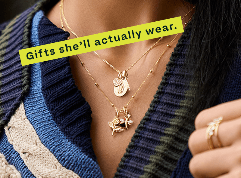 Model’s neck, wearing layered dainty gold necklaces with multiple pendants, including a heart & rose. Gifts she’ll actually wear.