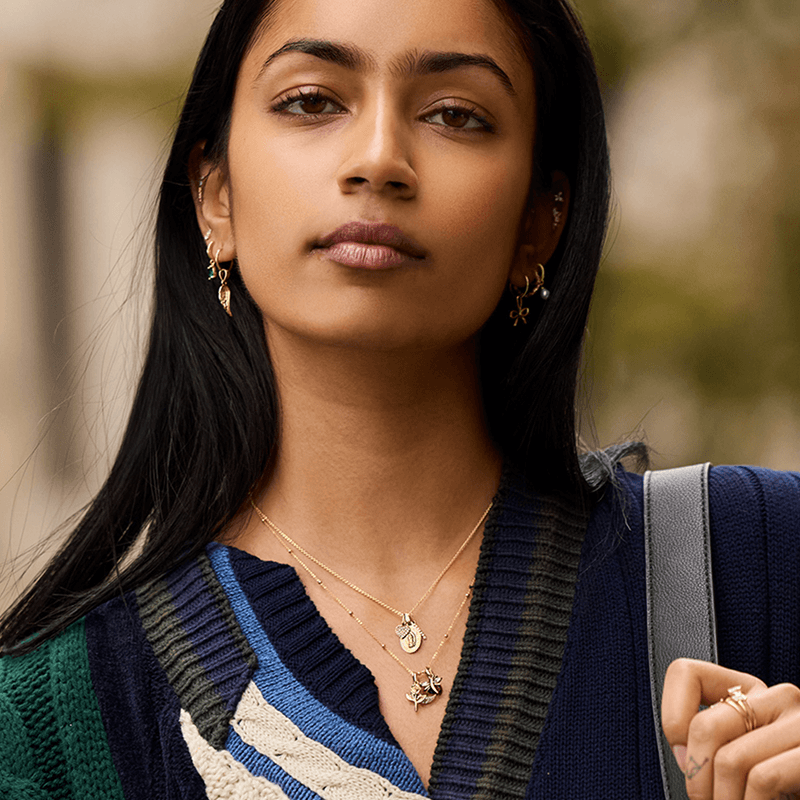 Model in gold station chains & earrings with mix of dangling pendants.