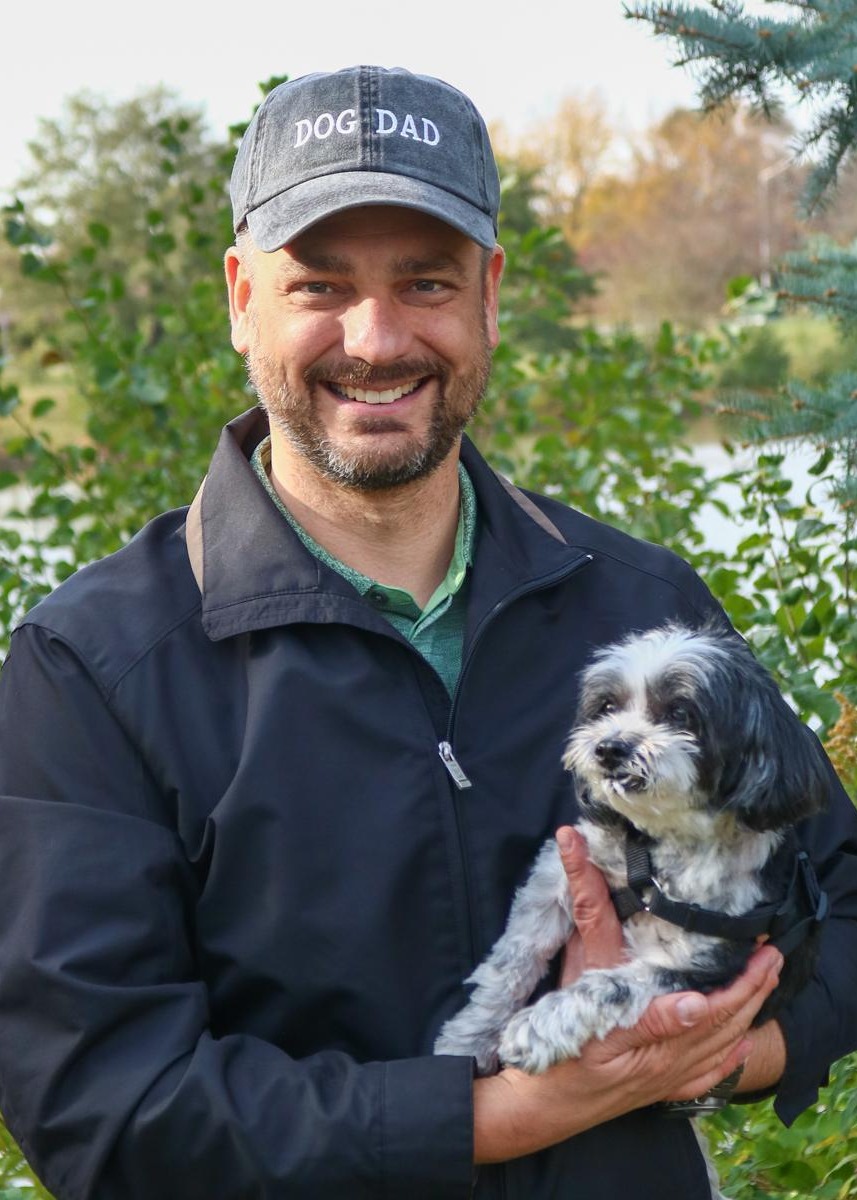 Man wearing a dog dad hat and holding a dog