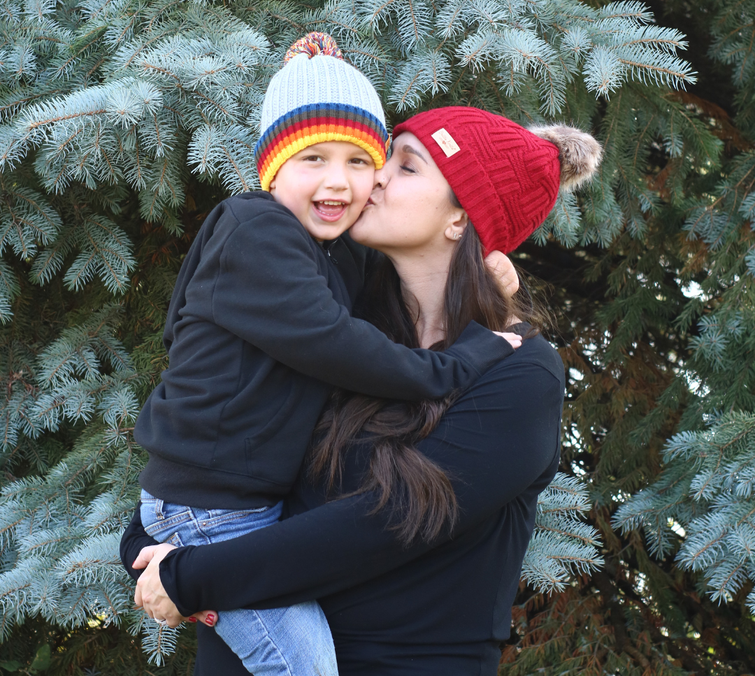 Woman holding her son and kissing him on the cheek