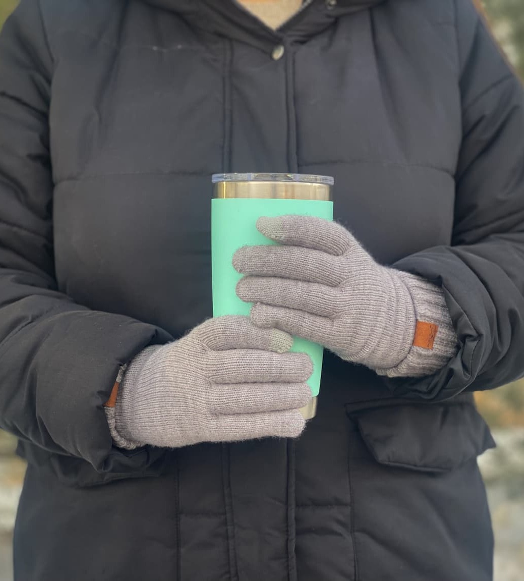 Woman wearing coat and holding coffee mug with gray gloves