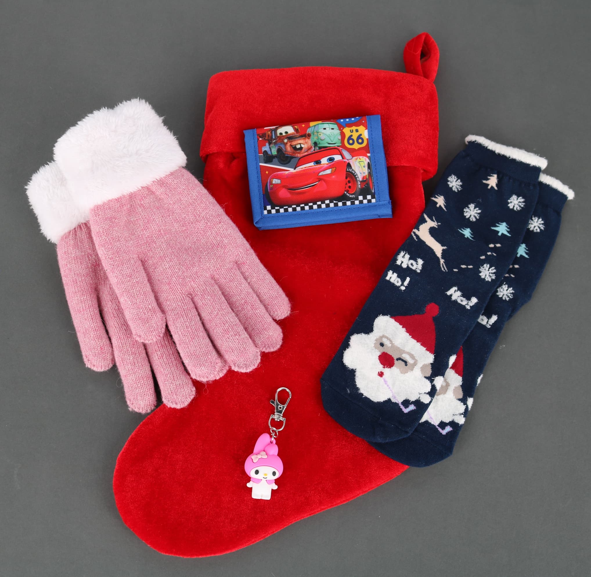 A red stocking with gloves, Santa socks, a cars wallet, and hello kitty bag charm