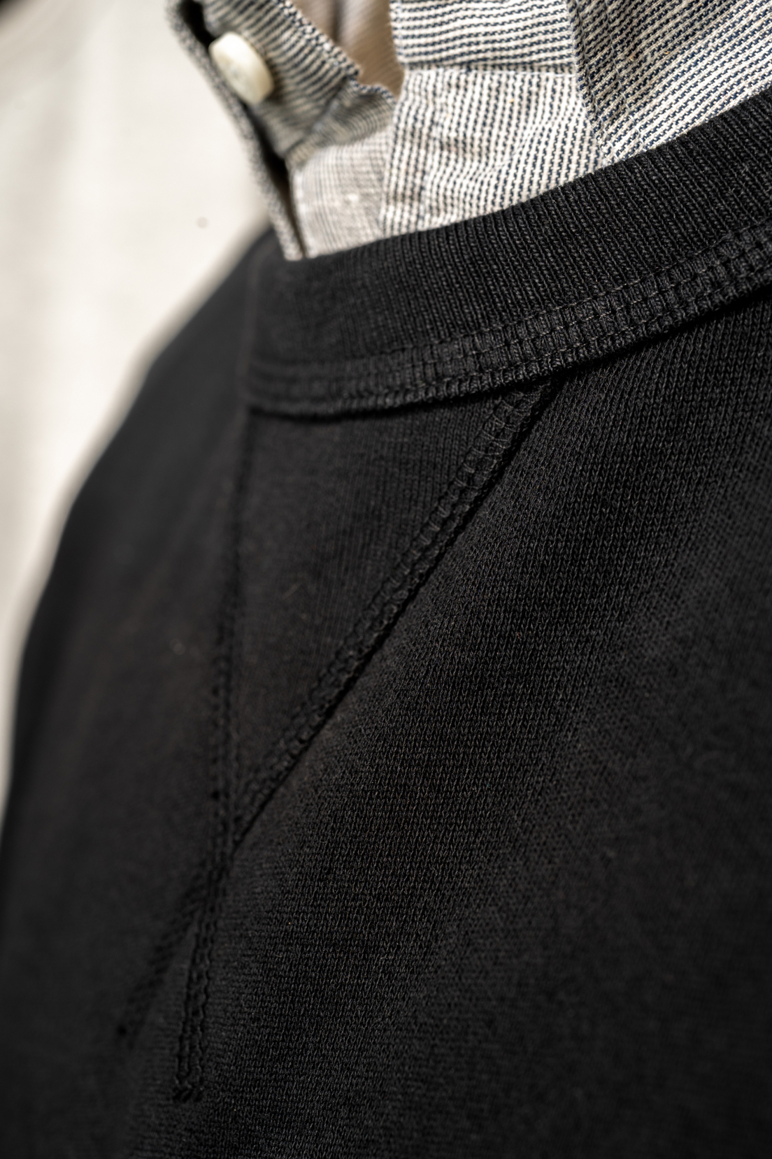 A close up of the front chest seam of a black Bills Khaki 100% Cotton Crewneck.