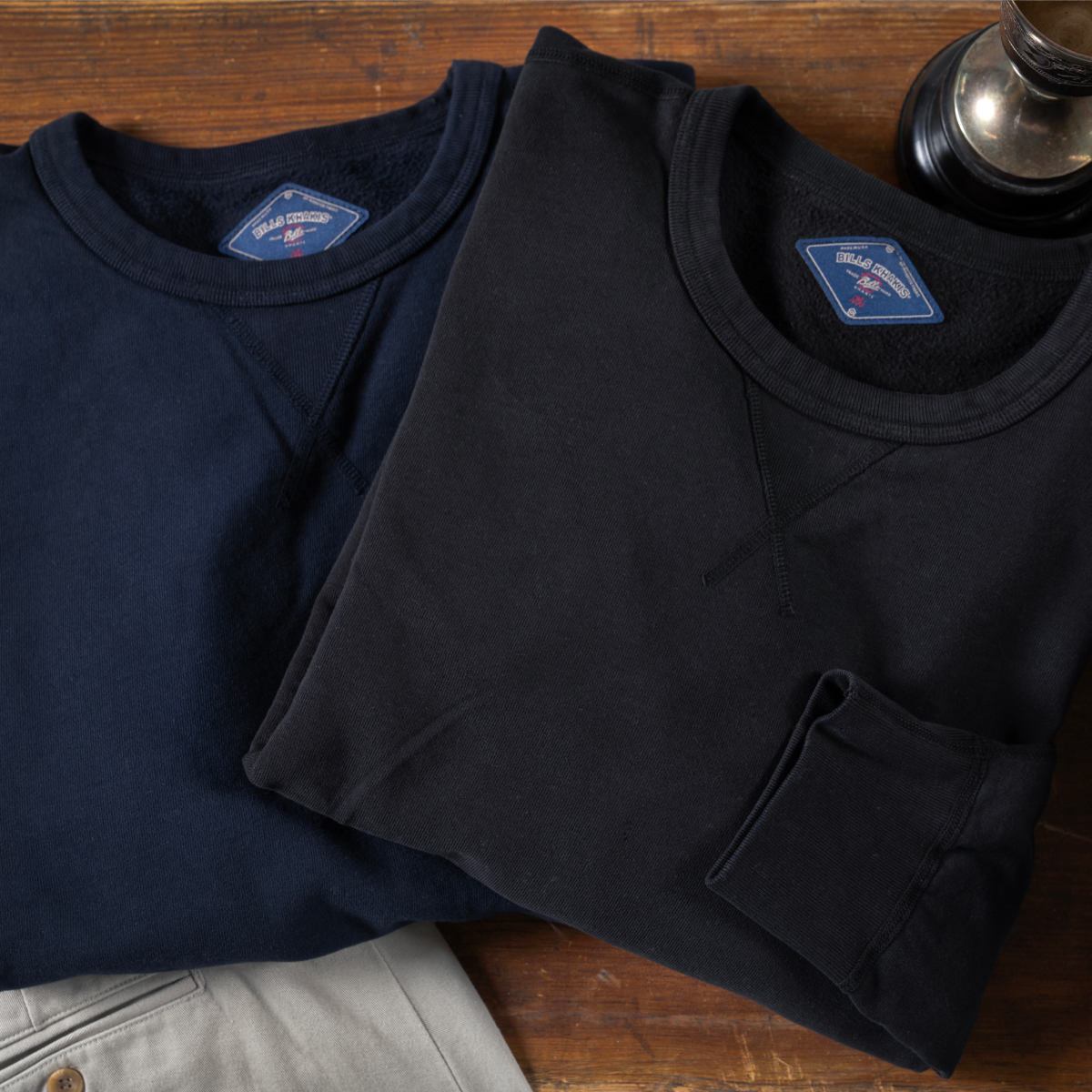 Classic 100% Cotton Crewnecks | A laydown of black and navy Bills Khakis Cotton Crewnecks