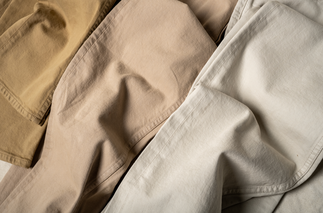 A crop-in macro shot of three pairs of Bills Khakis Bullard Twill pants showcasing the fabric texture and shadows