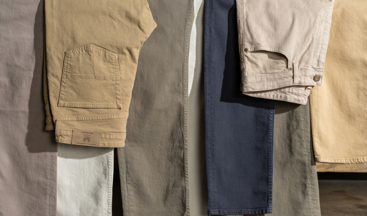 A full color array of Bills Khakis Bullard Twill Pants draped over a hanging bar
