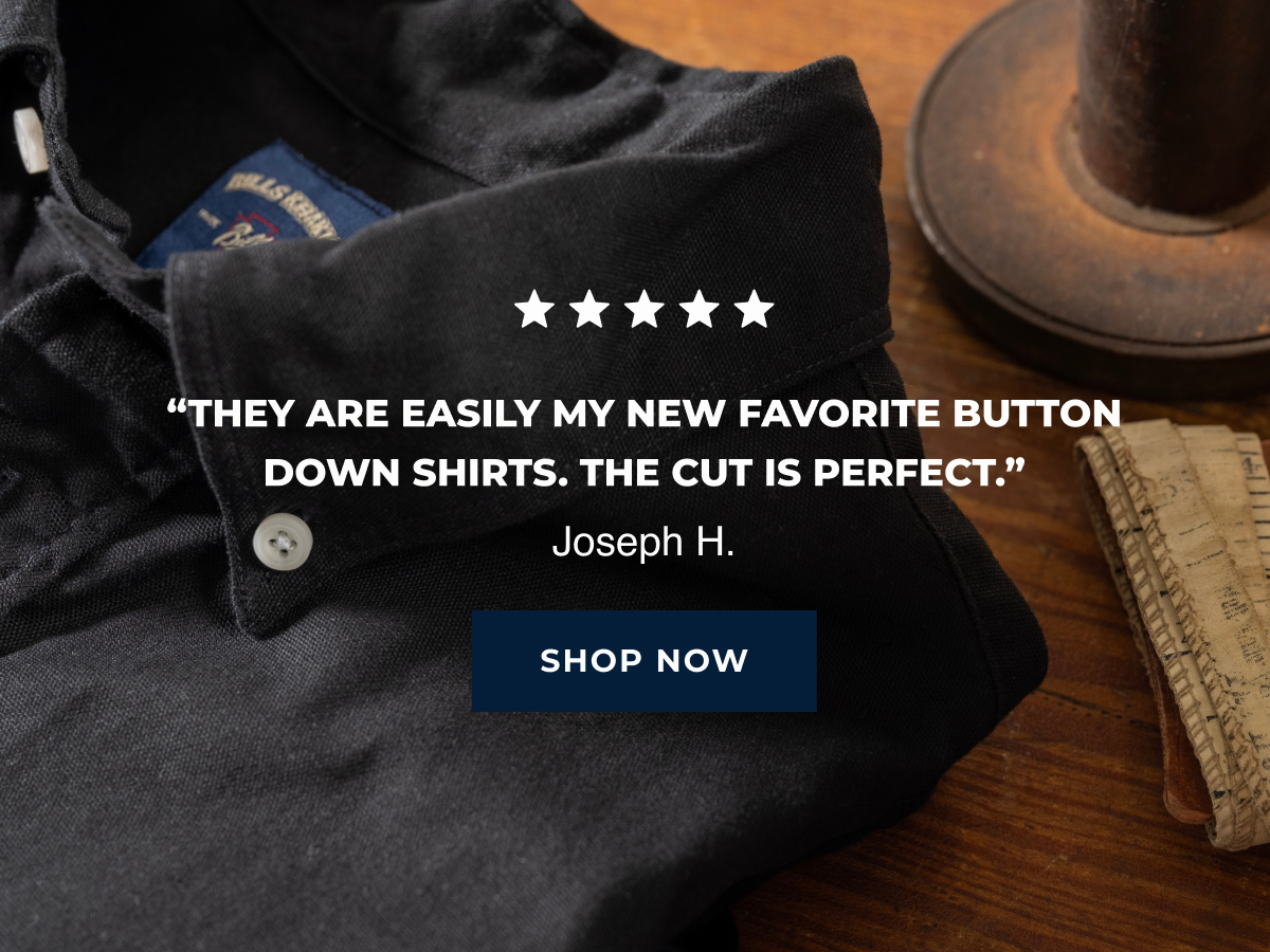 A black Bills Khakis American Oxford shirt sits in the foreground on a wooden table. Text reads 