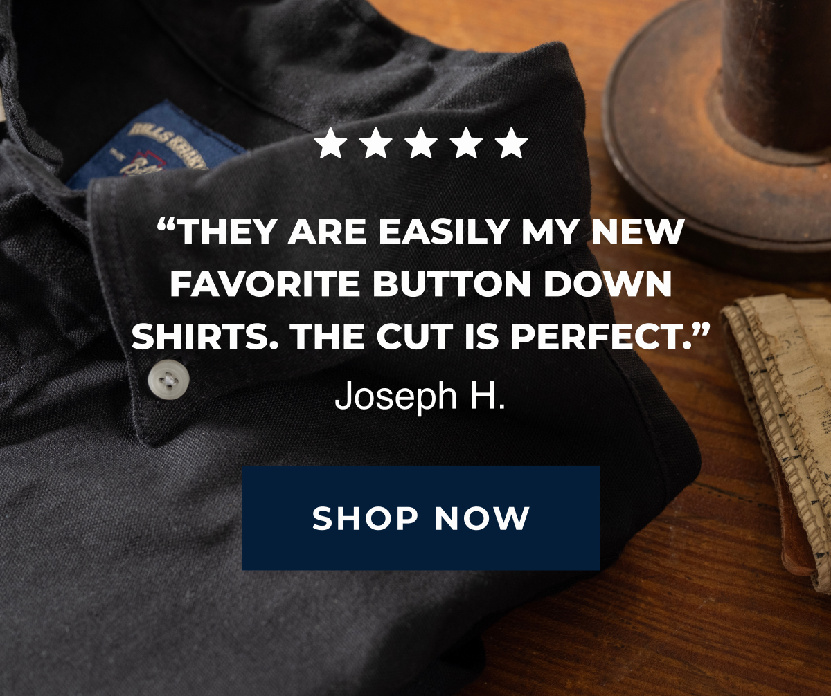 A black Bills Khakis American Oxford shirt sits in the foreground on a wooden table. Text reads 