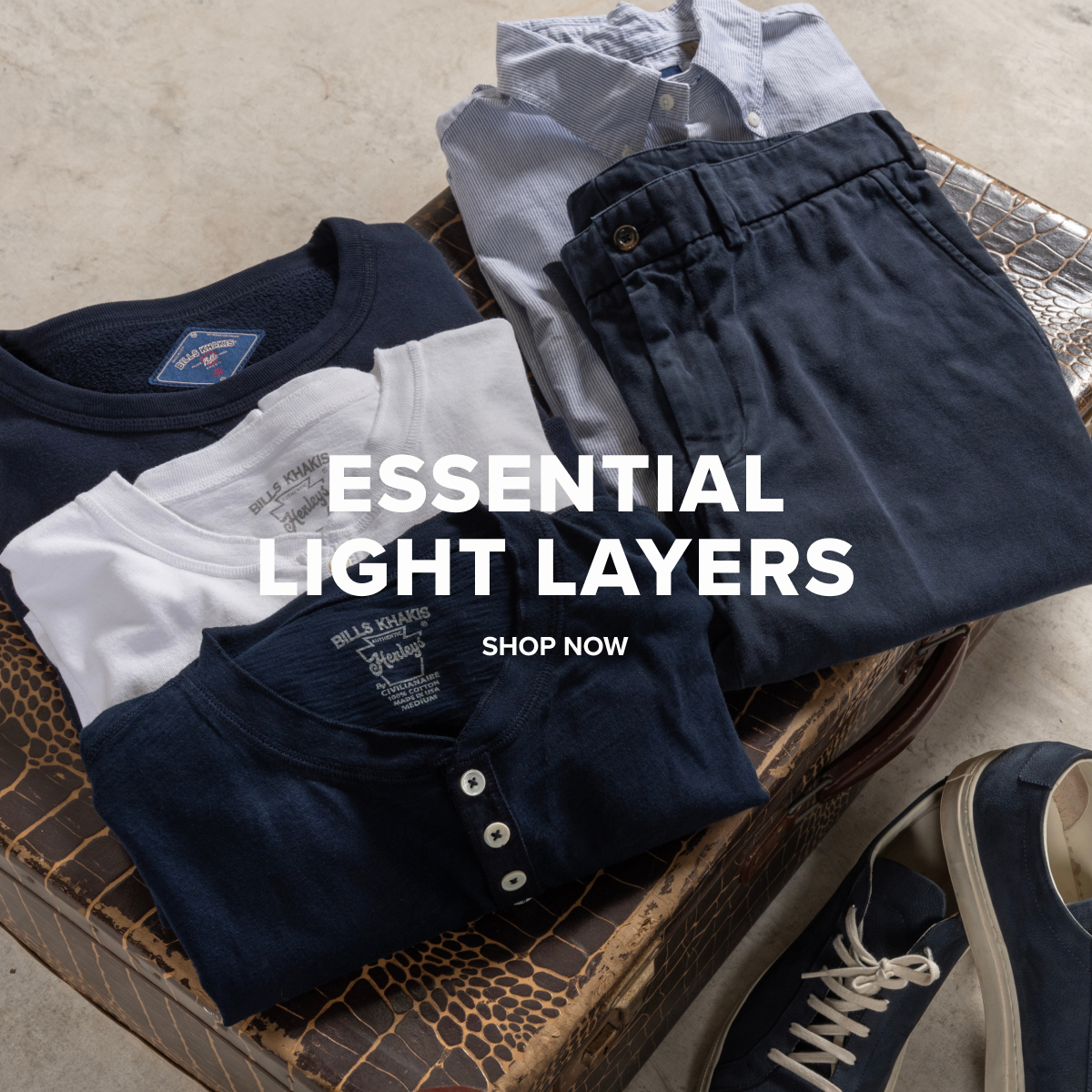 Various Bills Khakis lightweight henleys, classic crewnecks, brushed flannels sitting folded on a vintage suitcase. Text reads: Essential Light Layers | Shop Now