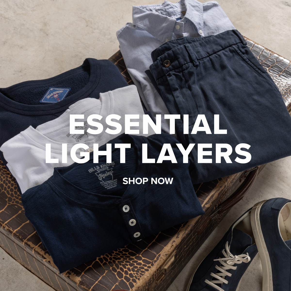 Various Bills Khakis lightweight henleys, classic crewnecks, brushed flannels sitting folded on a vintage suitcase. Text reads: Essential Light Layers | Shop Now