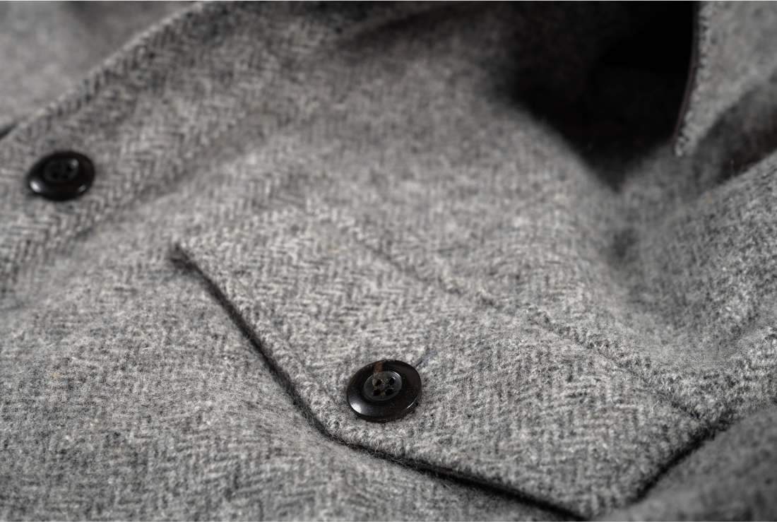 A close up of the pocket button of a grey Italian wool top from Bills Khakis