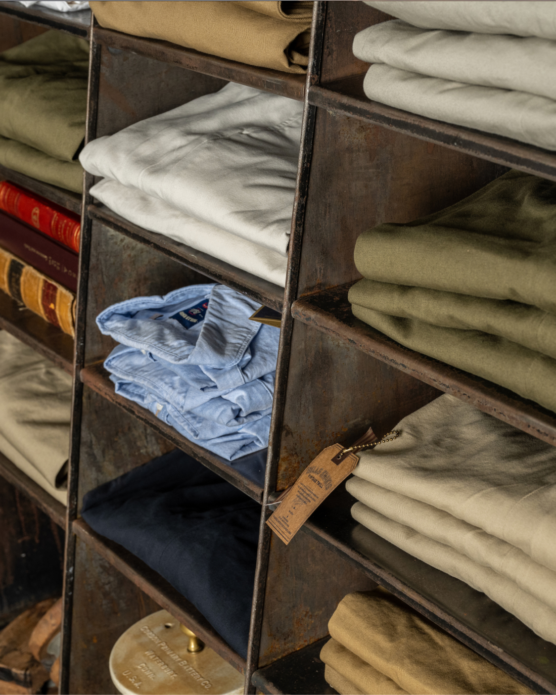 Industrial shelving shot froma left, downward angle with shelves filled with Bills Khakis garments