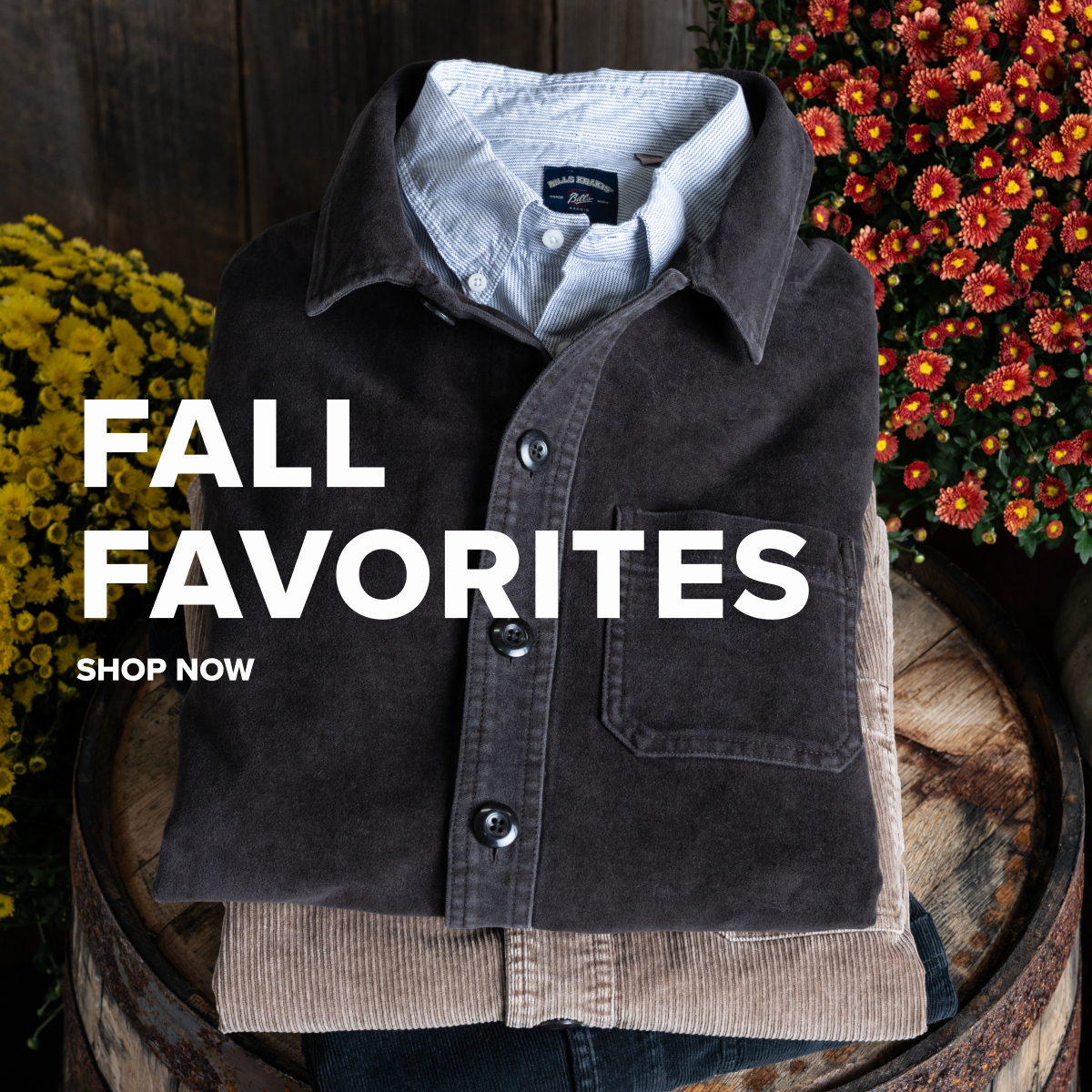 Folded Bills Khaki Chore Jackets sit on a vintage wood barrel donned by some yellow and red flowers
