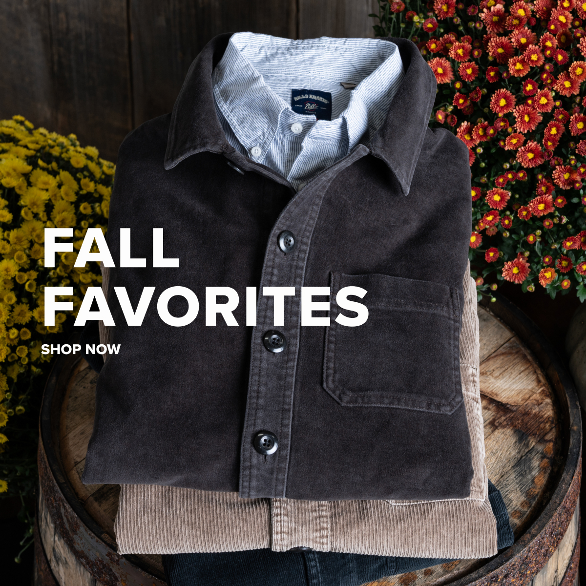 Folded Bills Khaki Chore Jackets sit on a vintage wood barrel donned by some yellow and red flowers