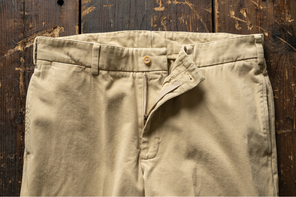 Bills Khaki M2 khaki colored Khakis pants sit on a dark wood surface