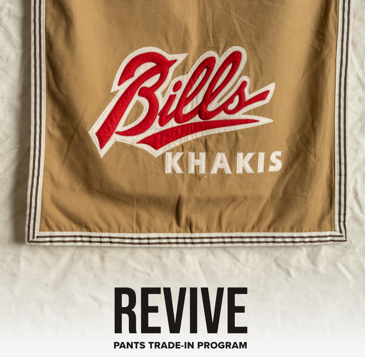 Revive Logo | Pants Trade-In Program logo ontop of an image of vintage Bills Khakis flag.