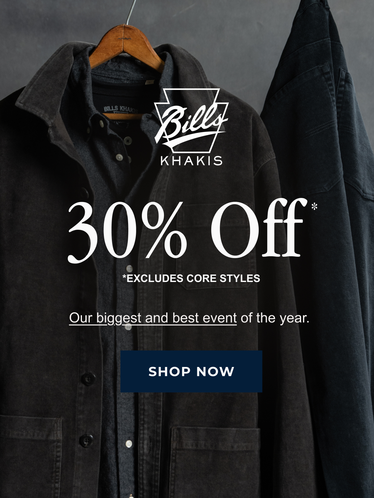 A black Bills Khaki Chore Jacket and charchoal Standard fit shirt hang against an industrial grey background alongside a pair of hanging navy Bills Khaki pants. The Bills Khaki logo overlays the image along with text that reads: 30% Off* | *Excludes Core styles | Our biggest and best event of the year | Shop Now