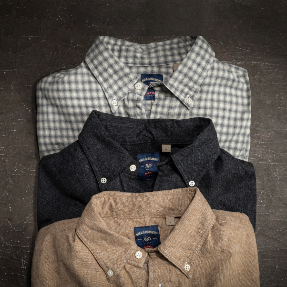 Three Bills Khakis standard fit shirts sit folded on a brown industrial surface