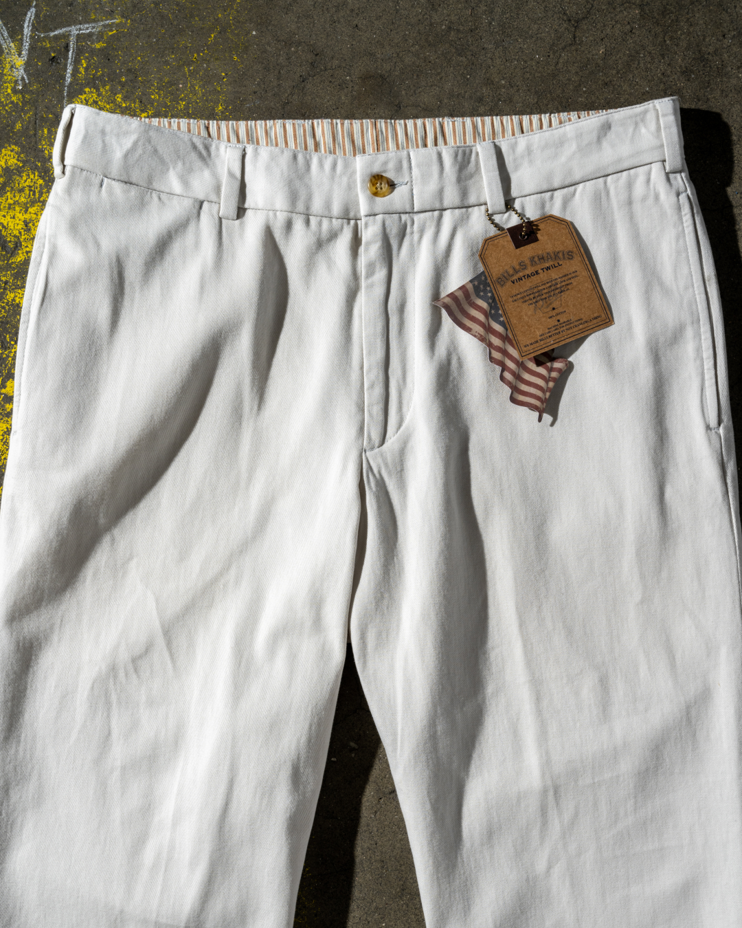 A close up oa Bills Khaki pant and tag on a concrete surface