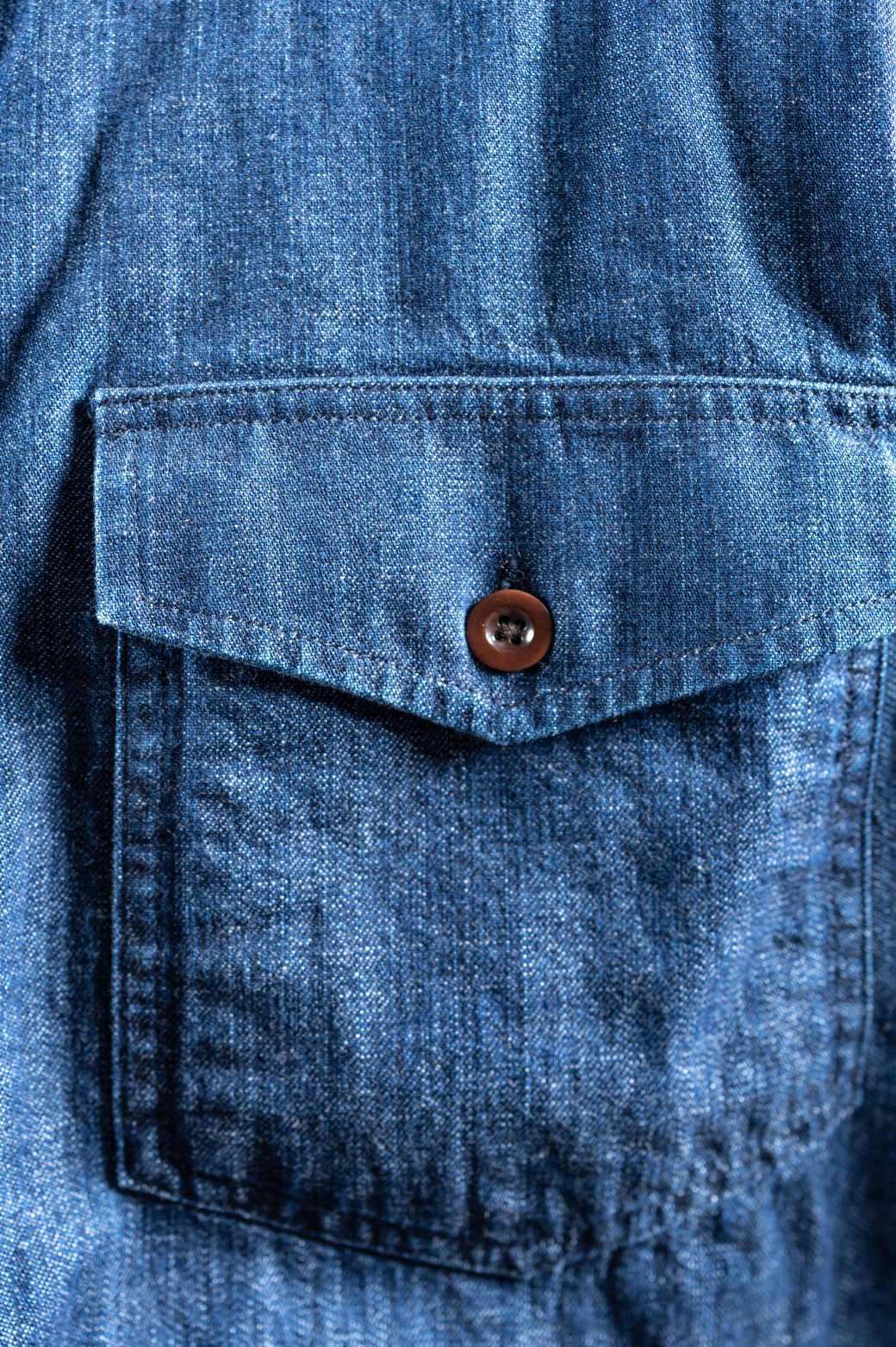 A hyper close up of the chest pocket area of a Bills Khakis light denim overshirt