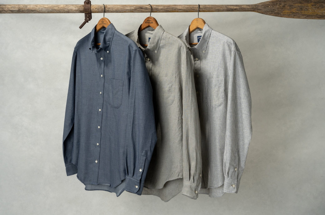 Three Bills Khakis Spring 2026 Standard Fit Shirts hang from hangers on a vintage wooden oar
