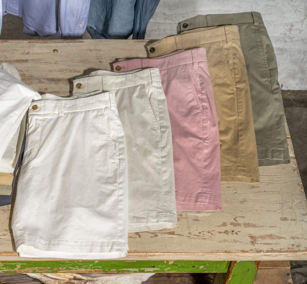 Pairs of Bills Khakis Keystone Twill Shorts laying on a word down wood table