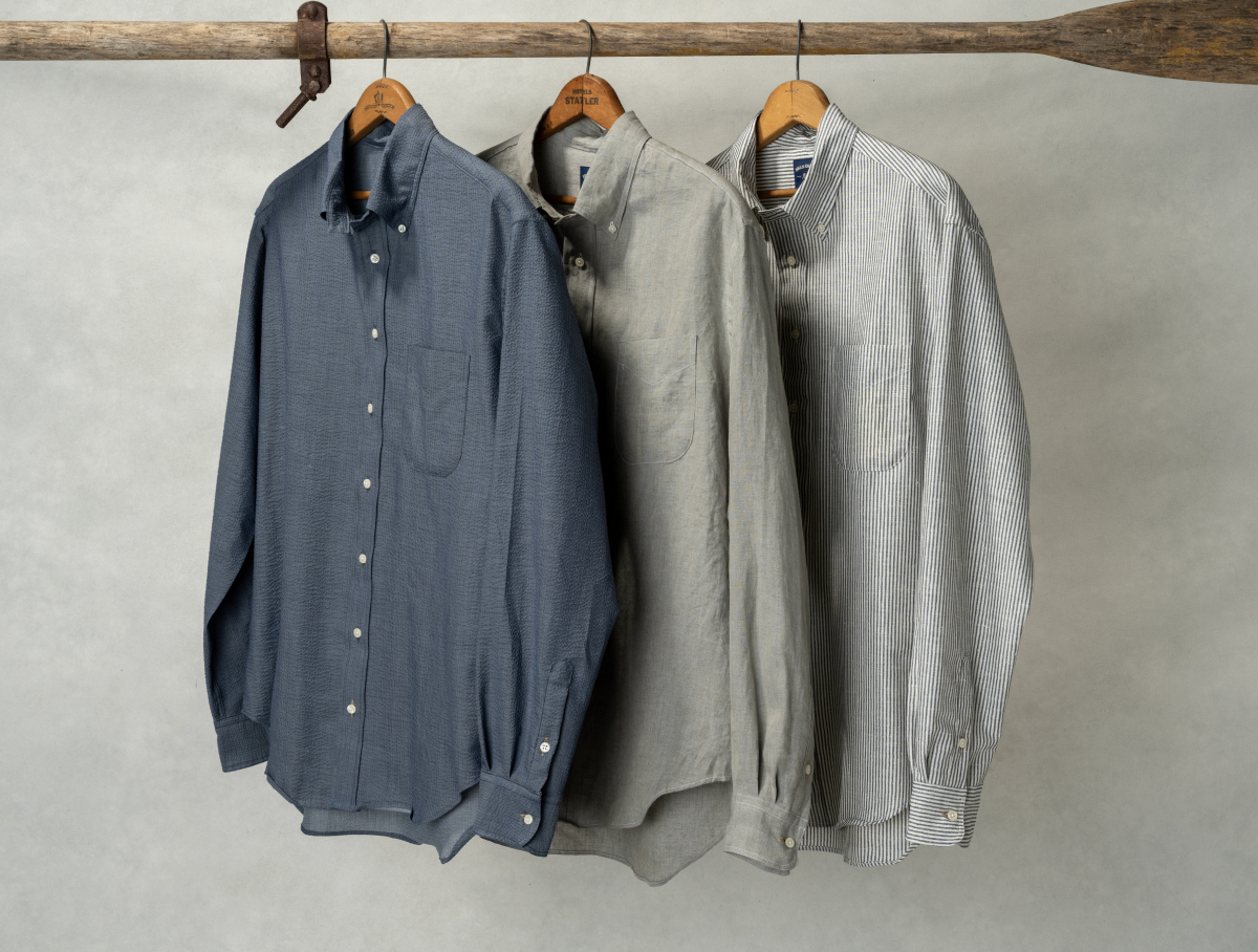 New Bills Khakis Seersucker, linen and cotton shirts hang from hangers off a wooden oar against a light backdrop