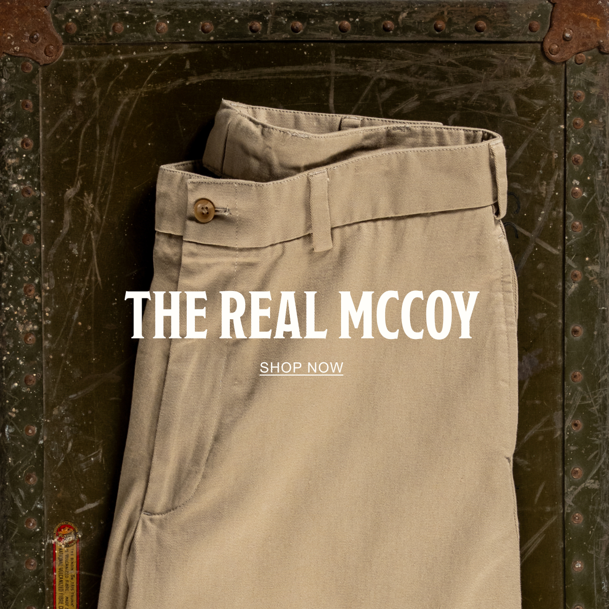 A pair of Bills Khakis Original Twill M1 Khakis on a vintage green chest. Text reads: The Real McCoy | Shop Now