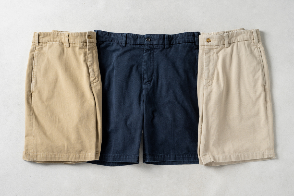 Three pairs of different color Bills Khakis Heritage Wash Shorts lay on a light surface