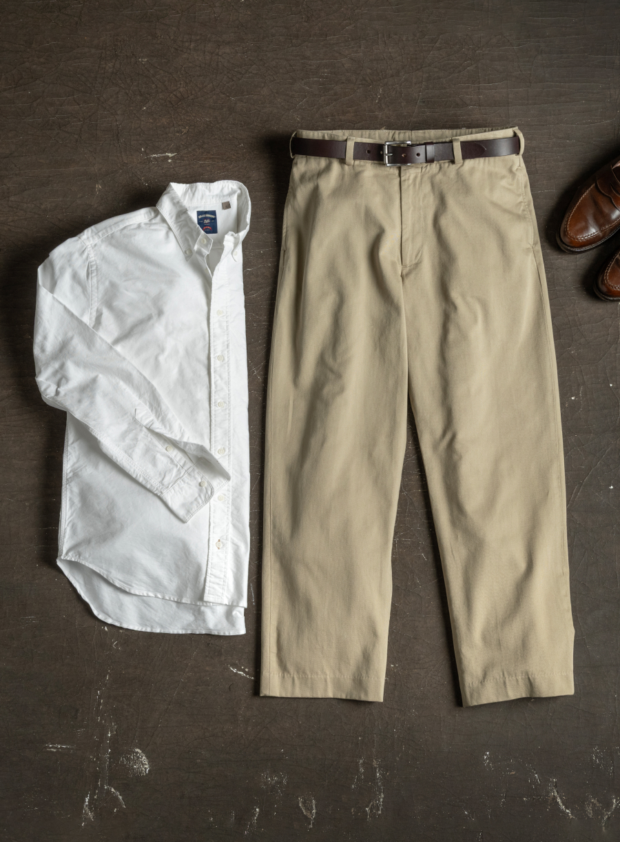 A white Bills Khakis standard fit shirt and signature style Bills Khakis Khaki lay on an industiral surface
