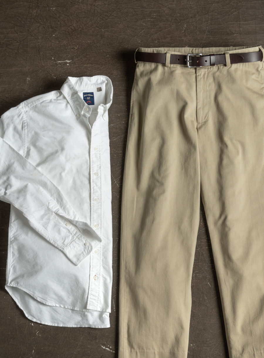 A Bills Khakis standard fit shirt and pair of classic khakis lay on an industrial surface