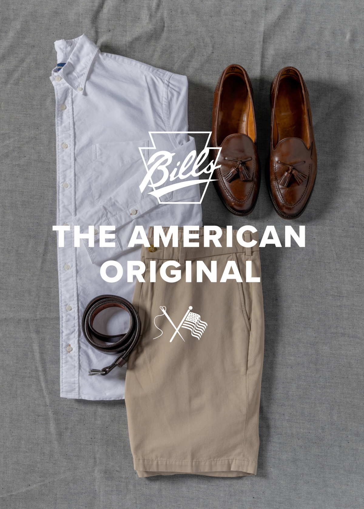 A timless Bills Khakis outfit consisting of shorts, belt, and standard fit shirt lays on a grey fabric surface