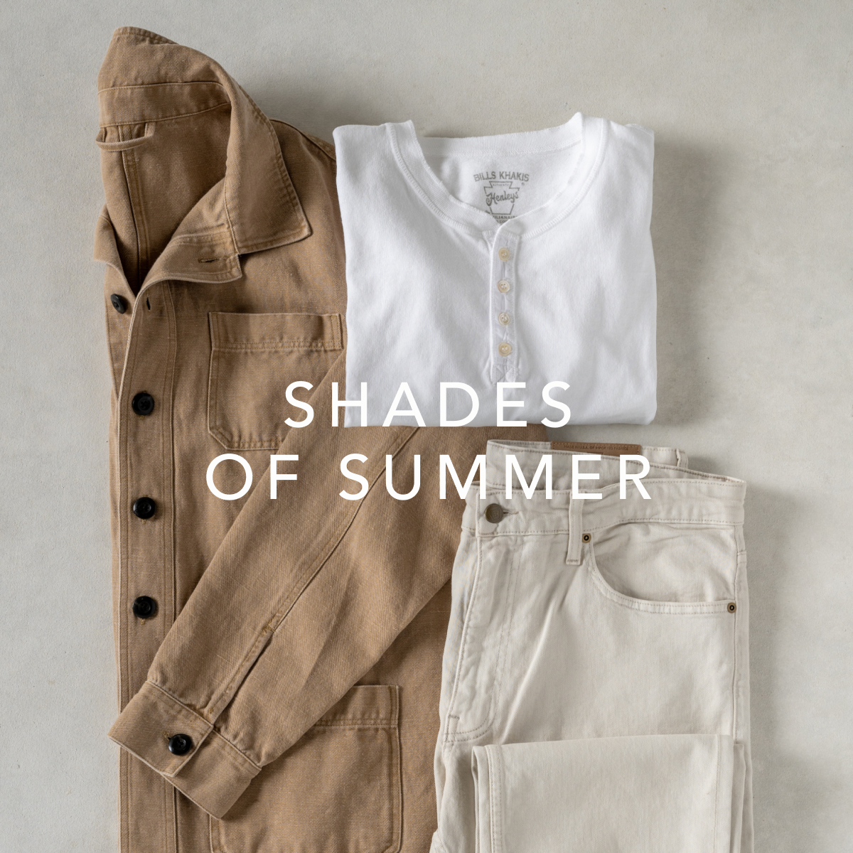 Light shades of Bills Khakis cloths - an overshirt, henly and pants - lay on a light colored surface
