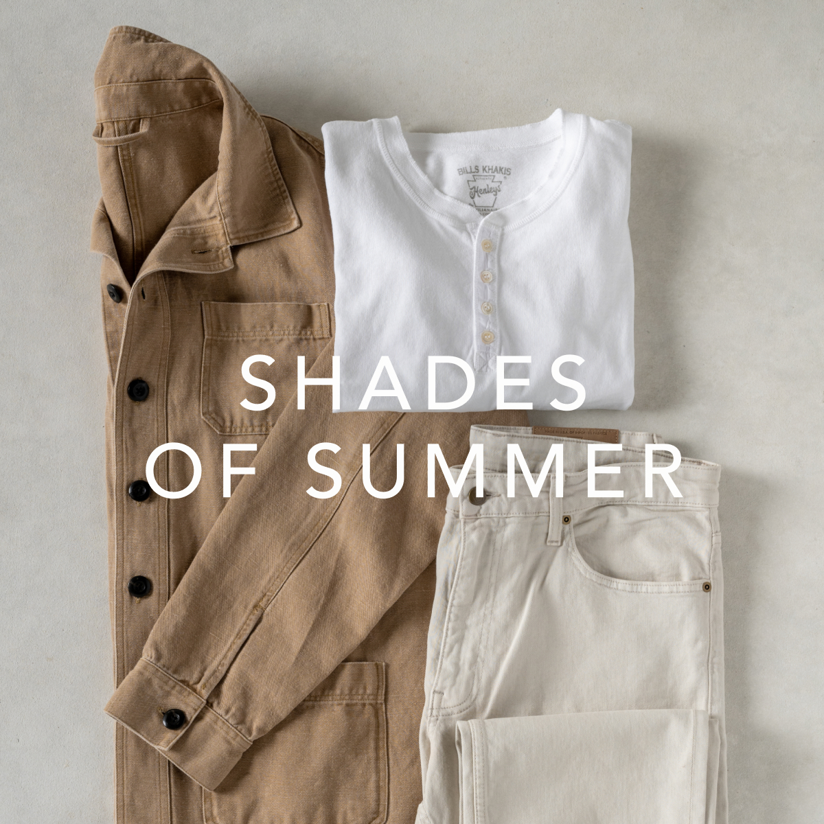 Light shades of Bills Khakis cloths - an overshirt, henly and pants - lay on a light colored surface