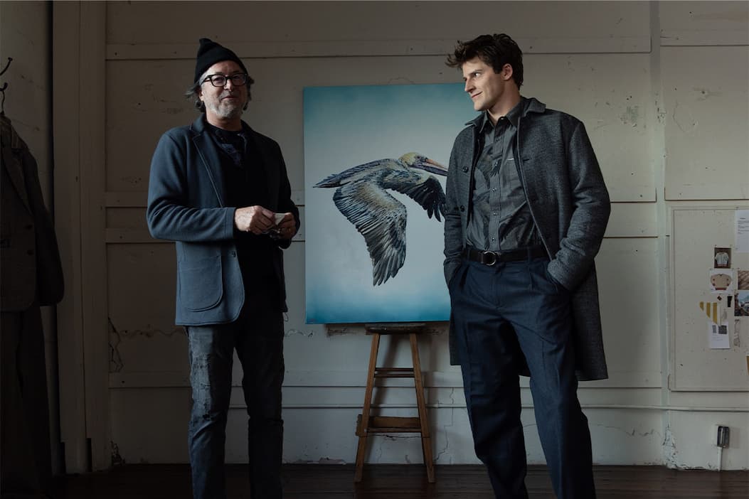 Billy poses for a photo with a model in front of a painting of a pelican