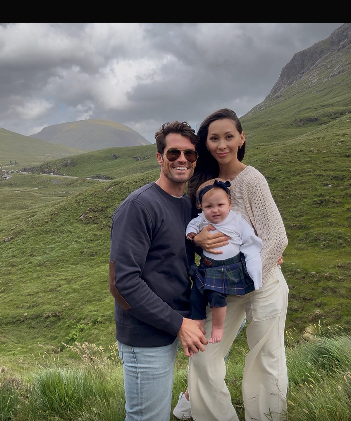 The family poses together on the hillside.