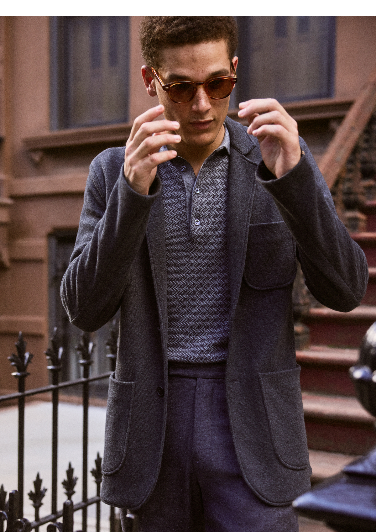 Model adjust his sunglasses. He wears the grey Heathered Knit Sport Coat