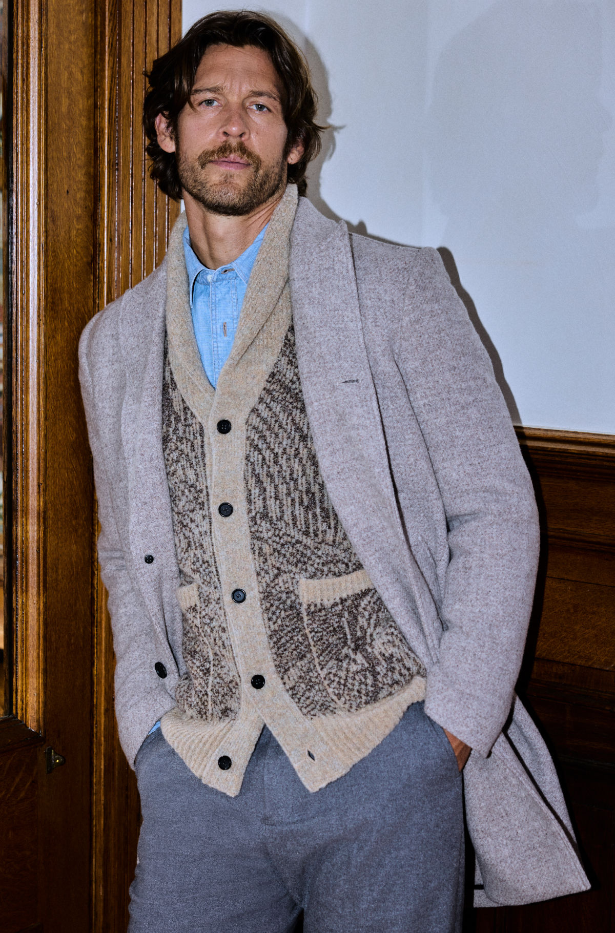 Model wears a layered fall outfit–a coat, carigan, and button down shirt.
