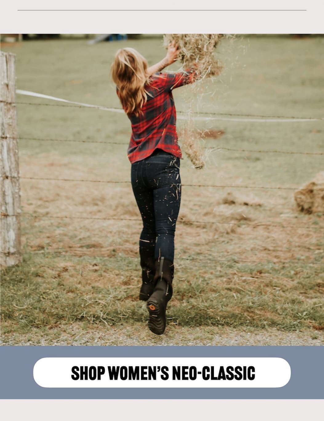 A woman throwing hay over a chain link fence